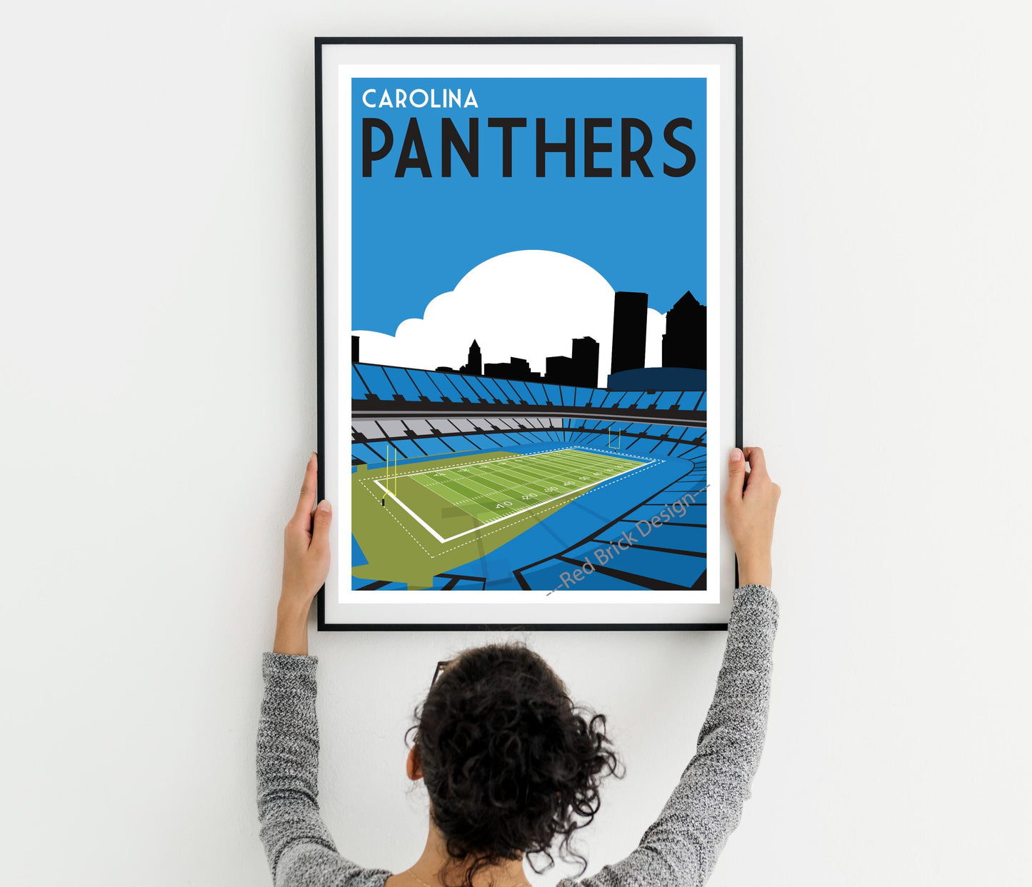 a woman holding up a framed poster of a stadium