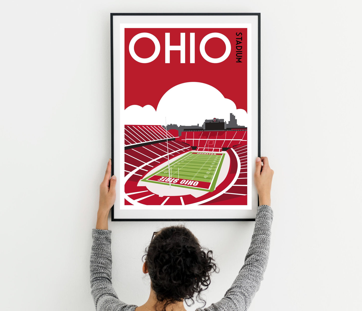 a woman holding up a poster of a stadium