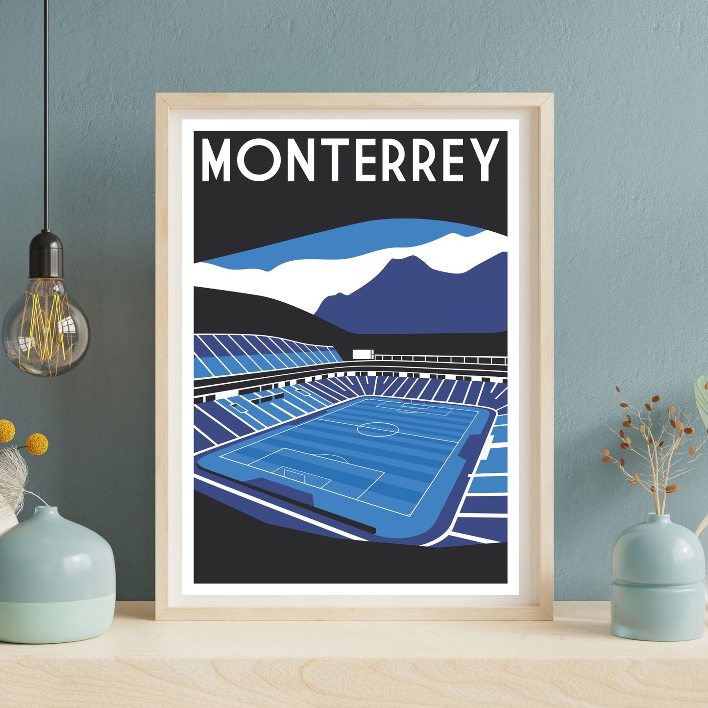 a framed illustration of a soccer stadium with mountains in the background.