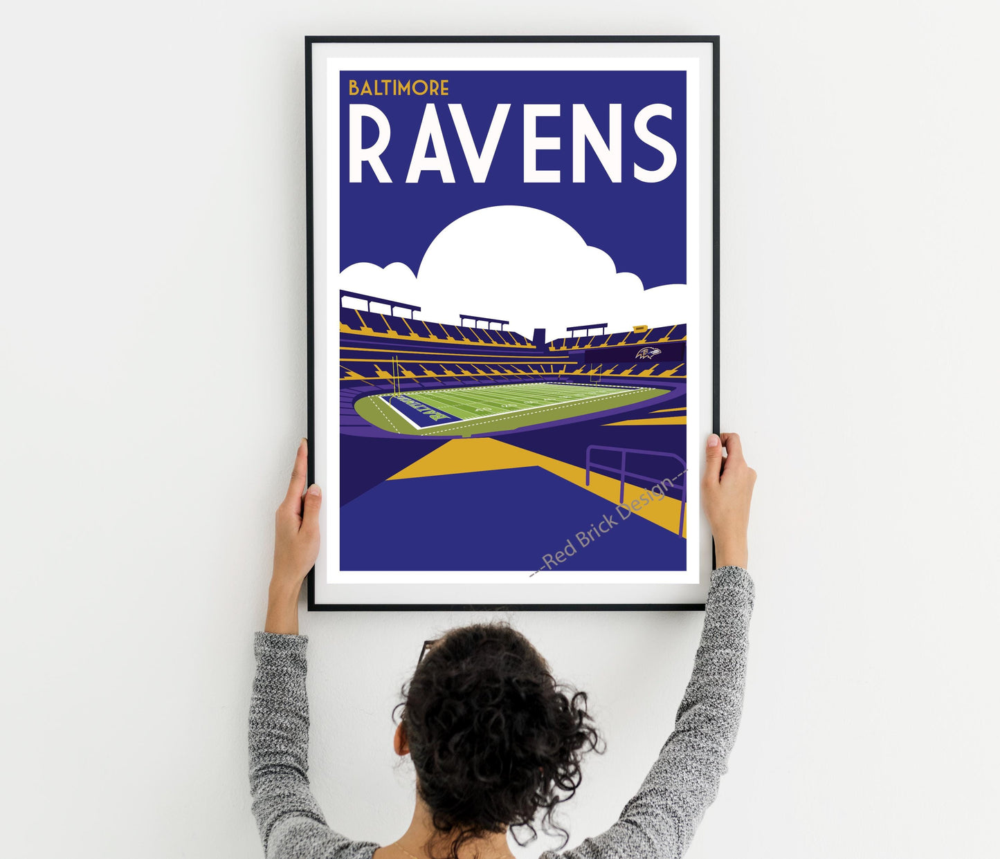 a woman holding up a framed poster of a stadium