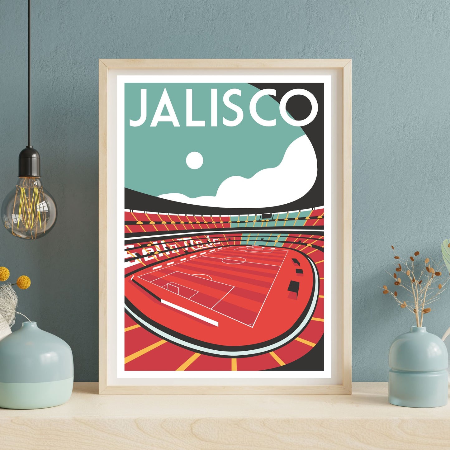 A framed poster depicting a soccer stadium with a red field and white lines, set against a blue sky with a white moon.
