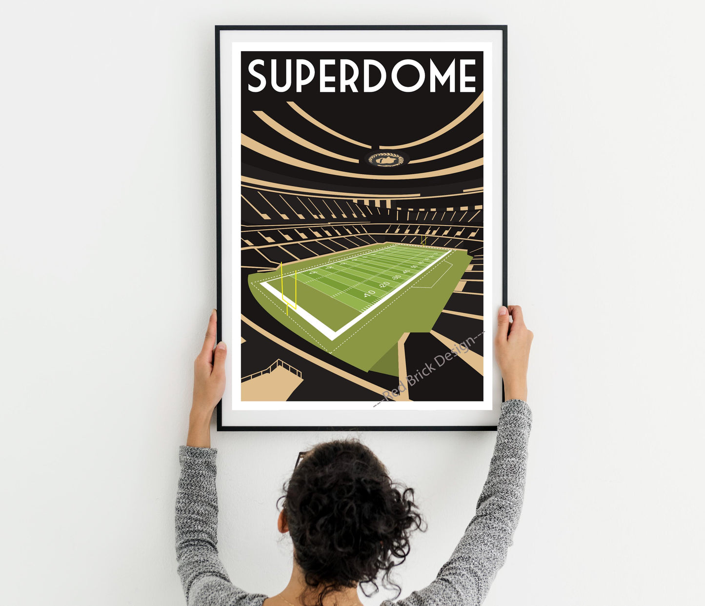 a woman holding up a framed poster of a stadium