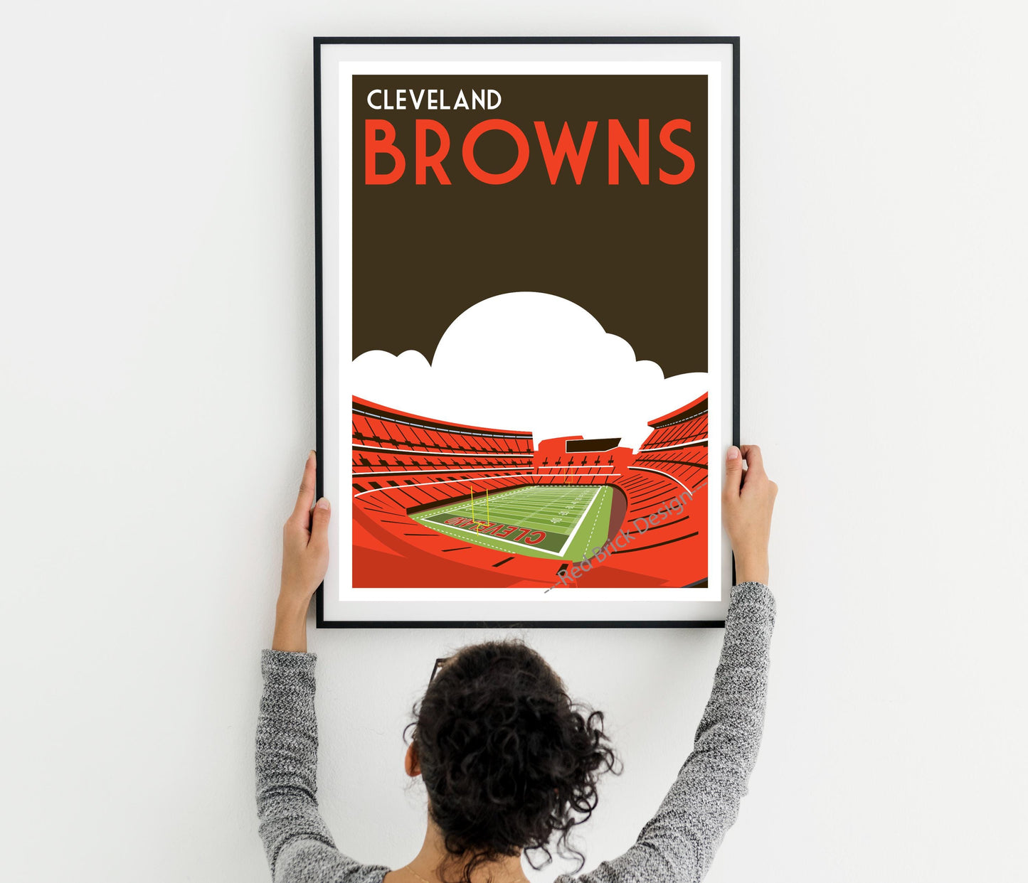 a woman holding up a framed poster of a stadium