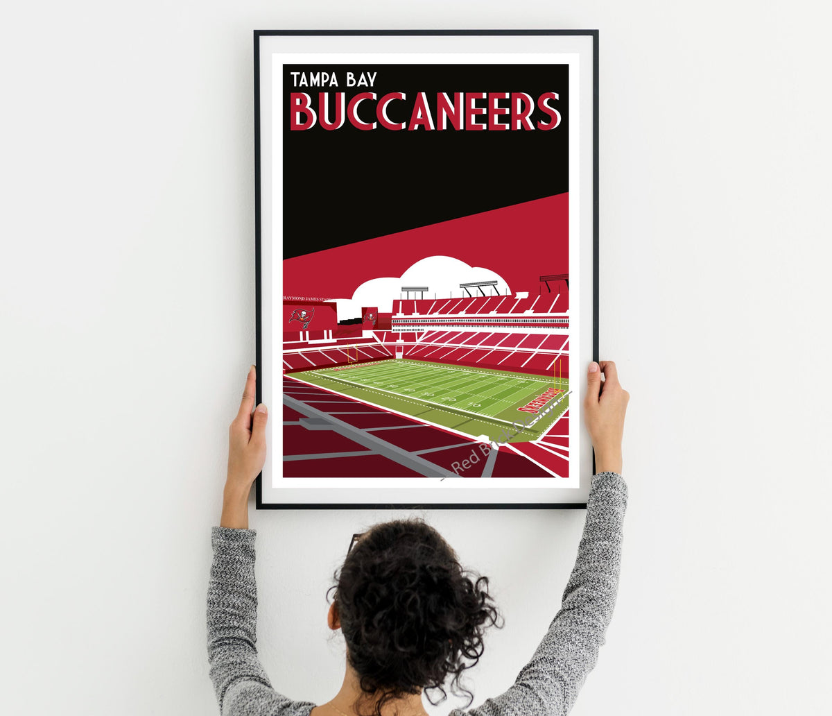 a woman holding up a framed poster of a stadium