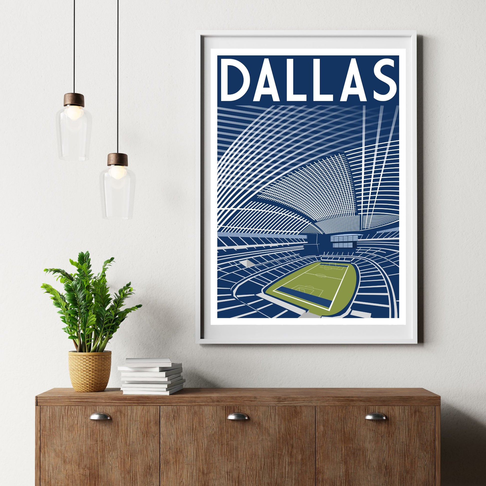 a framed poster of a stadium with a plant on a wooden dresser below it.