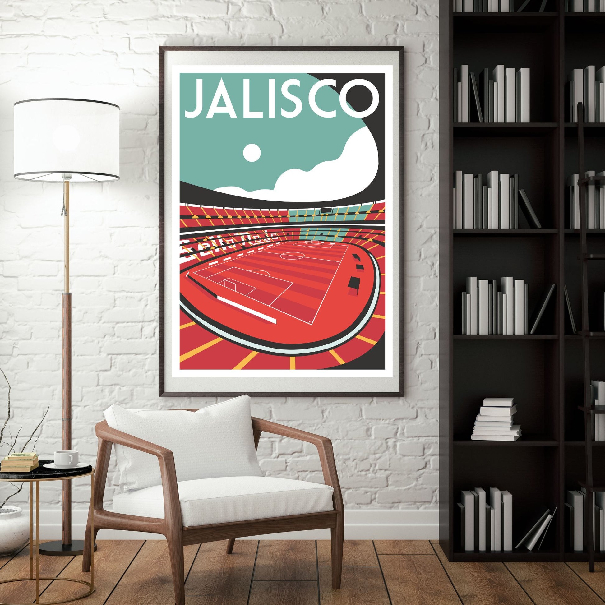 a framed poster of a stadium with a red field and white lines, hanging on a white brick wall. In front of the poster, there is a white chair and a bookshelf filled with books.