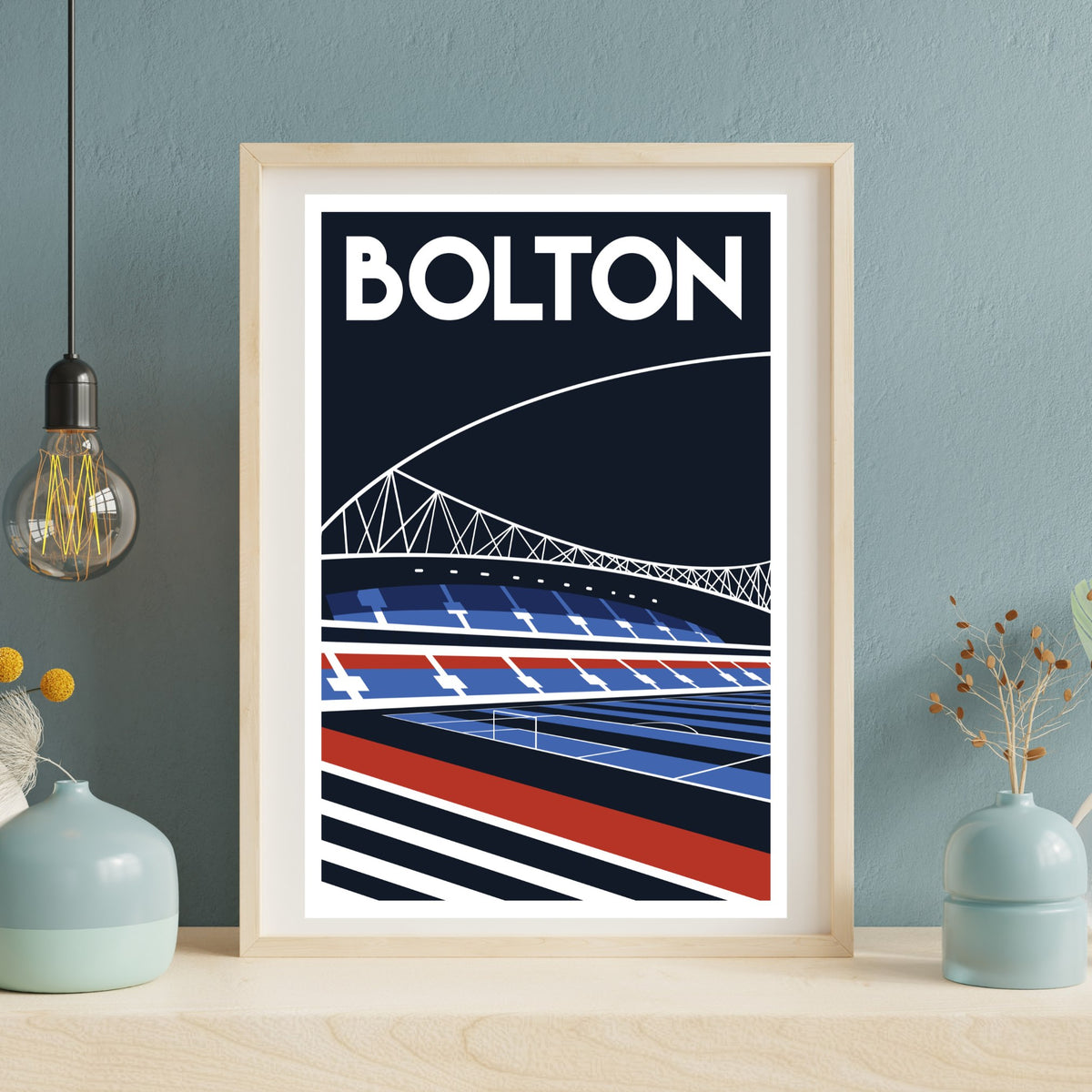 A framed poster of a stadium with a bridge in the background, featuring the word "BOLTON" prominently displayed.