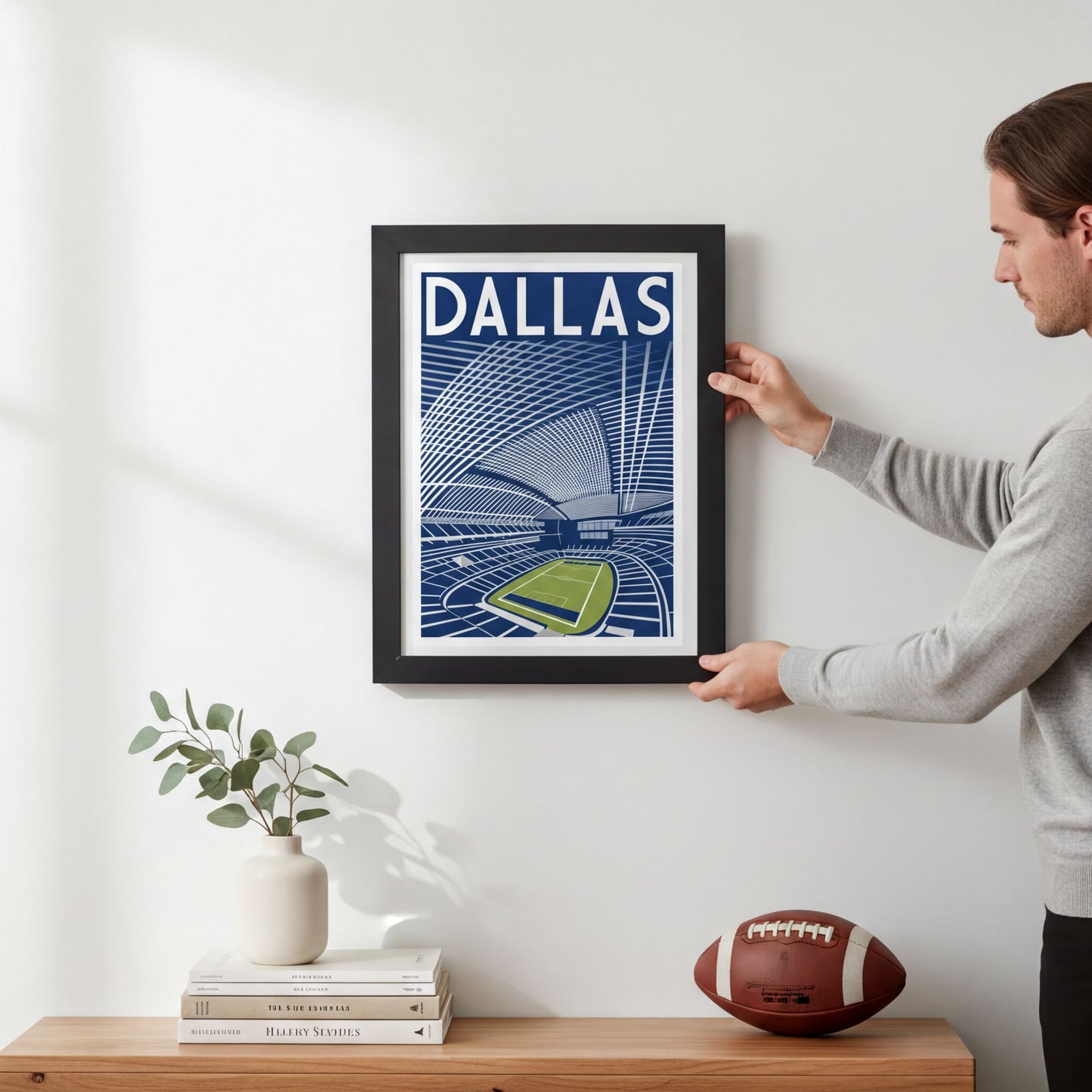A framed poster of a stadium is hanging on a wall, with a person standing next to it.