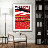 a framed poster of Arsenal Emirates Stadium hanging on a wall, with a white chair in the foreground and a bookshelf filled with books to the right.