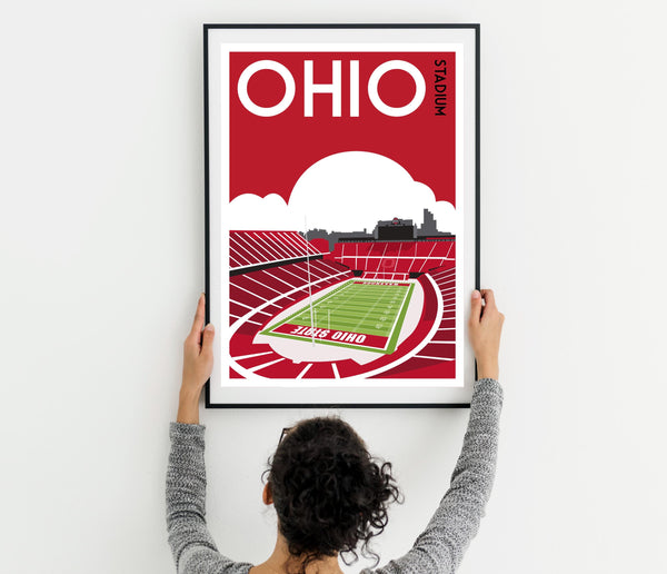a woman holding up a poster of a stadium