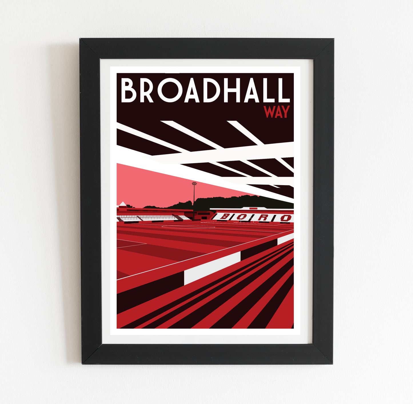The image is a framed poster depicting a sports stadium, specifically Broadhall Way, with a red and black color scheme.