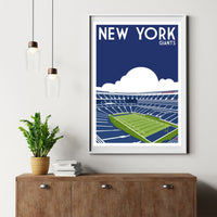 a framed poster of a football stadium with the text "NEW YORK GIANTS" on it, hanging on a wall above a wooden dresser.
