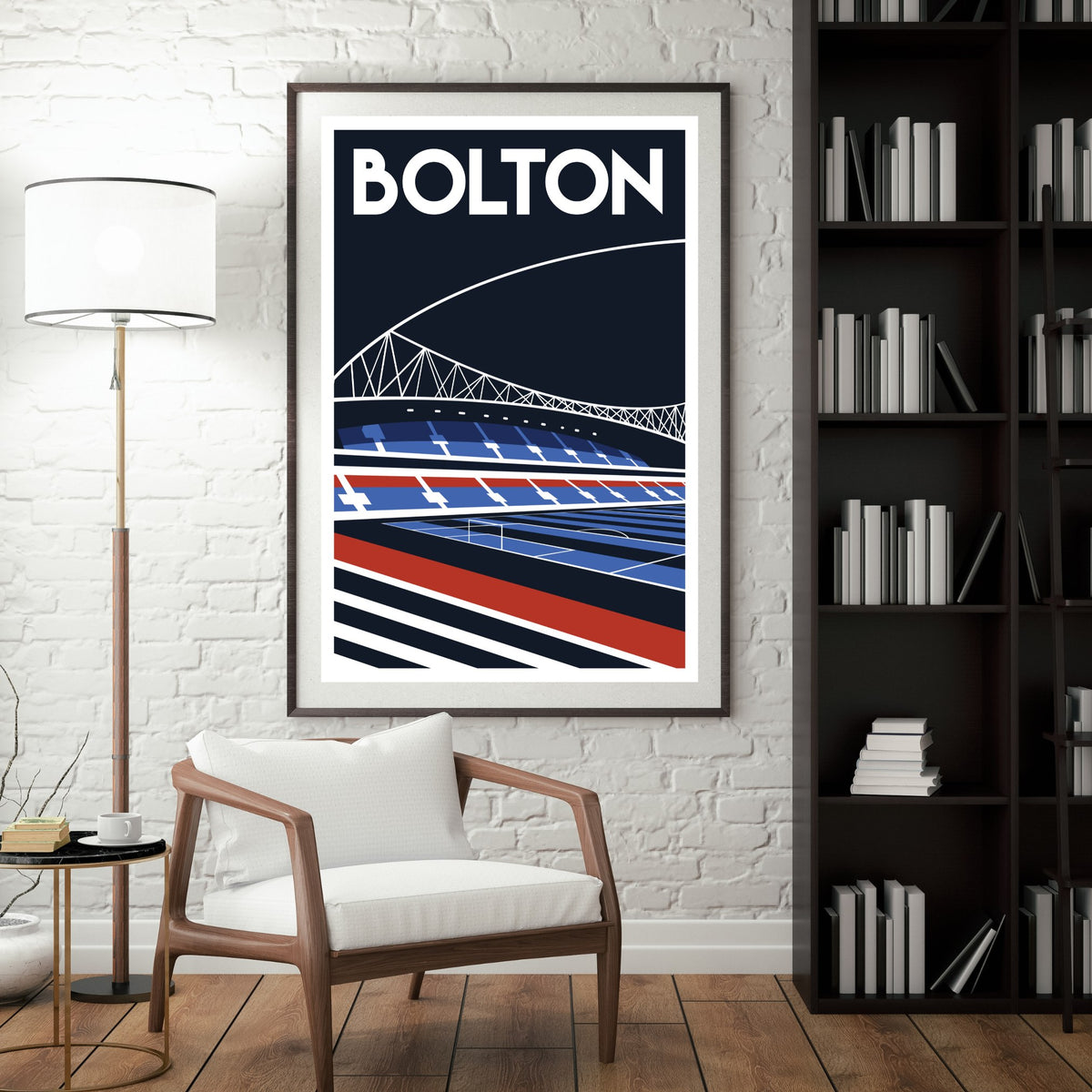 a framed poster of a stadium with a bridge in the background, hanging on a wall next to a bookshelf filled with books.