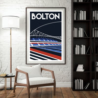 a framed poster of a stadium with a bridge in the background, hanging on a wall next to a bookshelf filled with books.