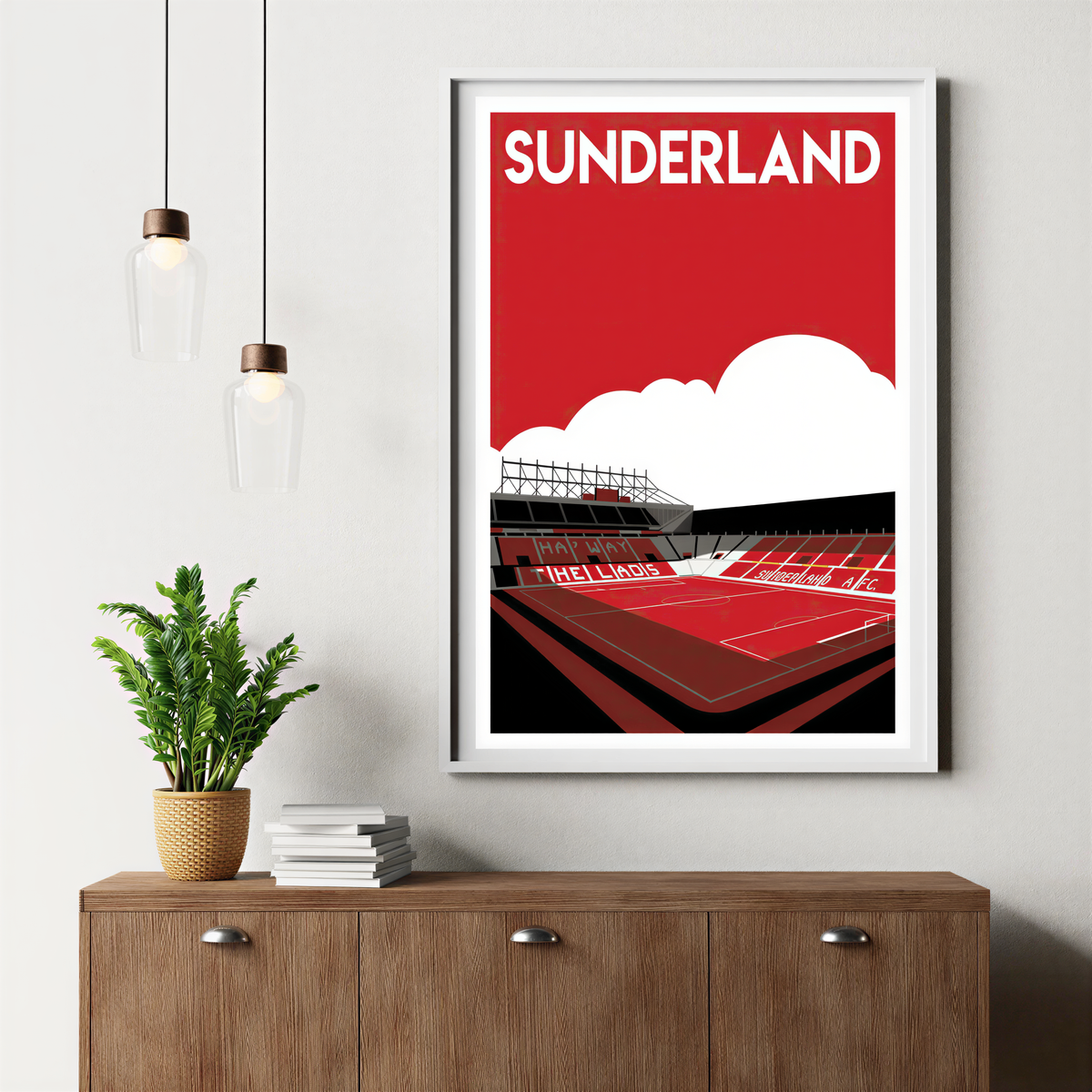 a framed poster of a stadium with the word "Sunderland" written on it, hanging on a wall above a wooden cabinet.