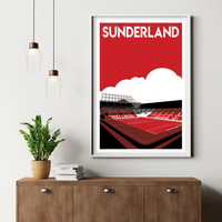 a framed poster of a stadium with the word "Sunderland" written on it, hanging on a wall above a wooden cabinet.