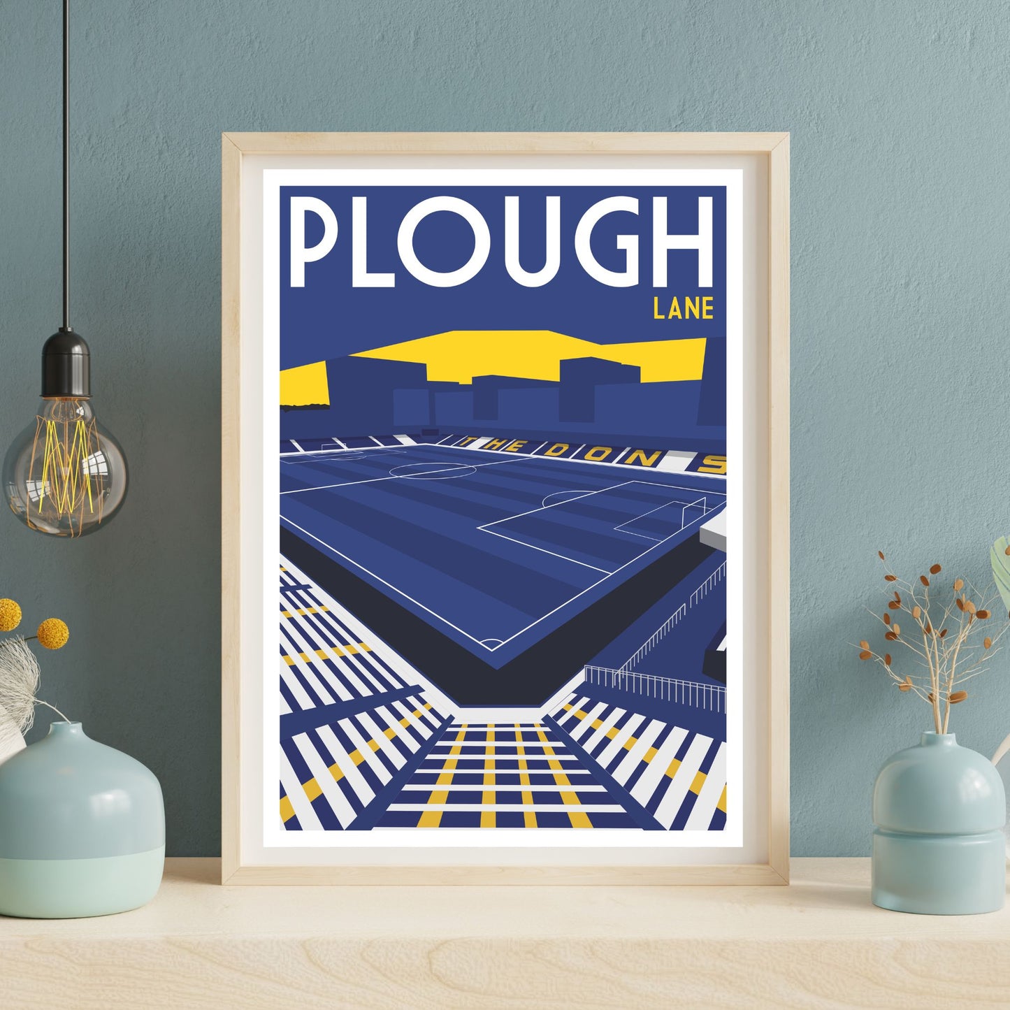 a framed poster of a stadium with a blue and yellow color scheme, depicting a soccer field and seating area.