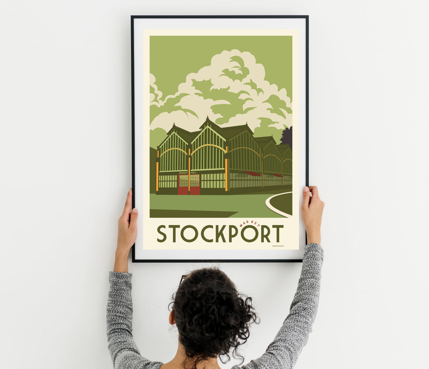 a woman holding up a poster with a picture of Stockport Market