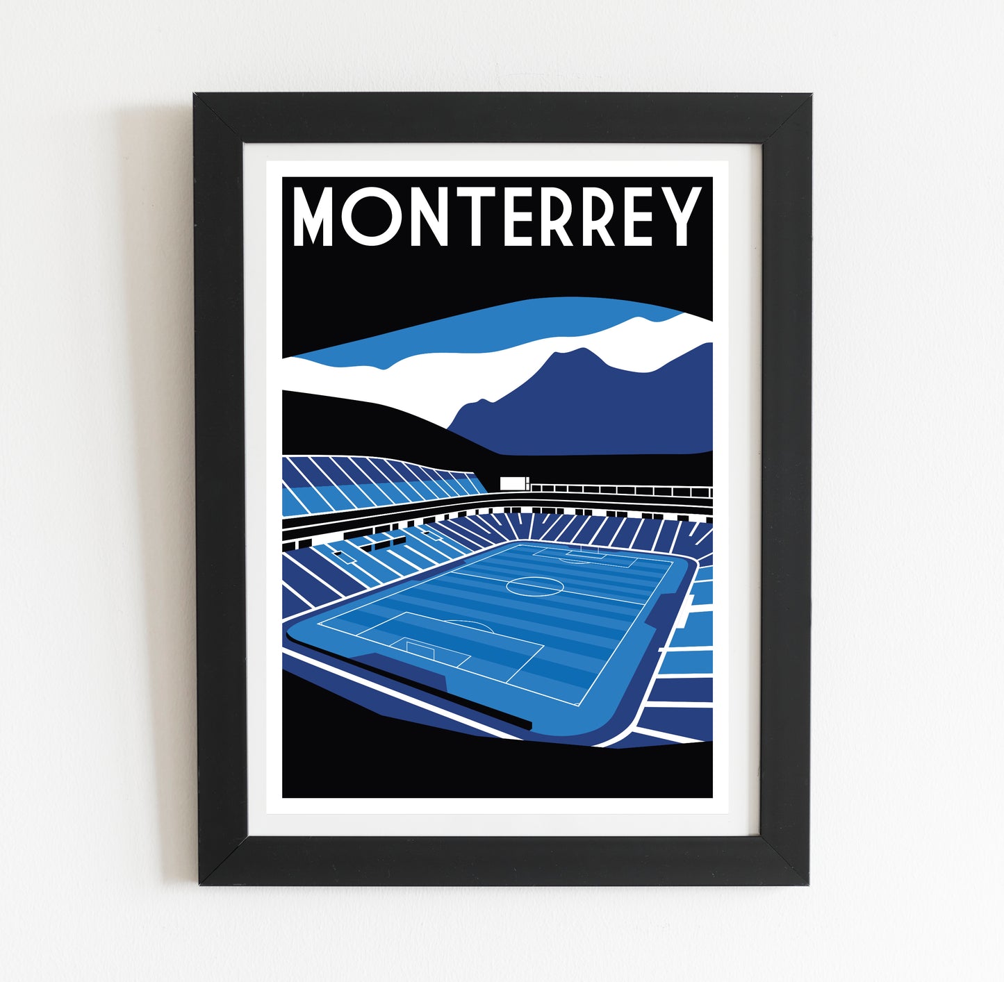 The image is a framed poster depicting a soccer stadium with mountains in the background.