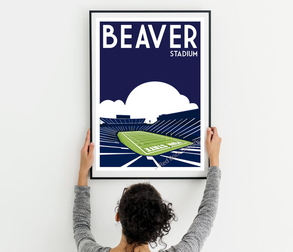 a woman holding up a framed poster of a stadium