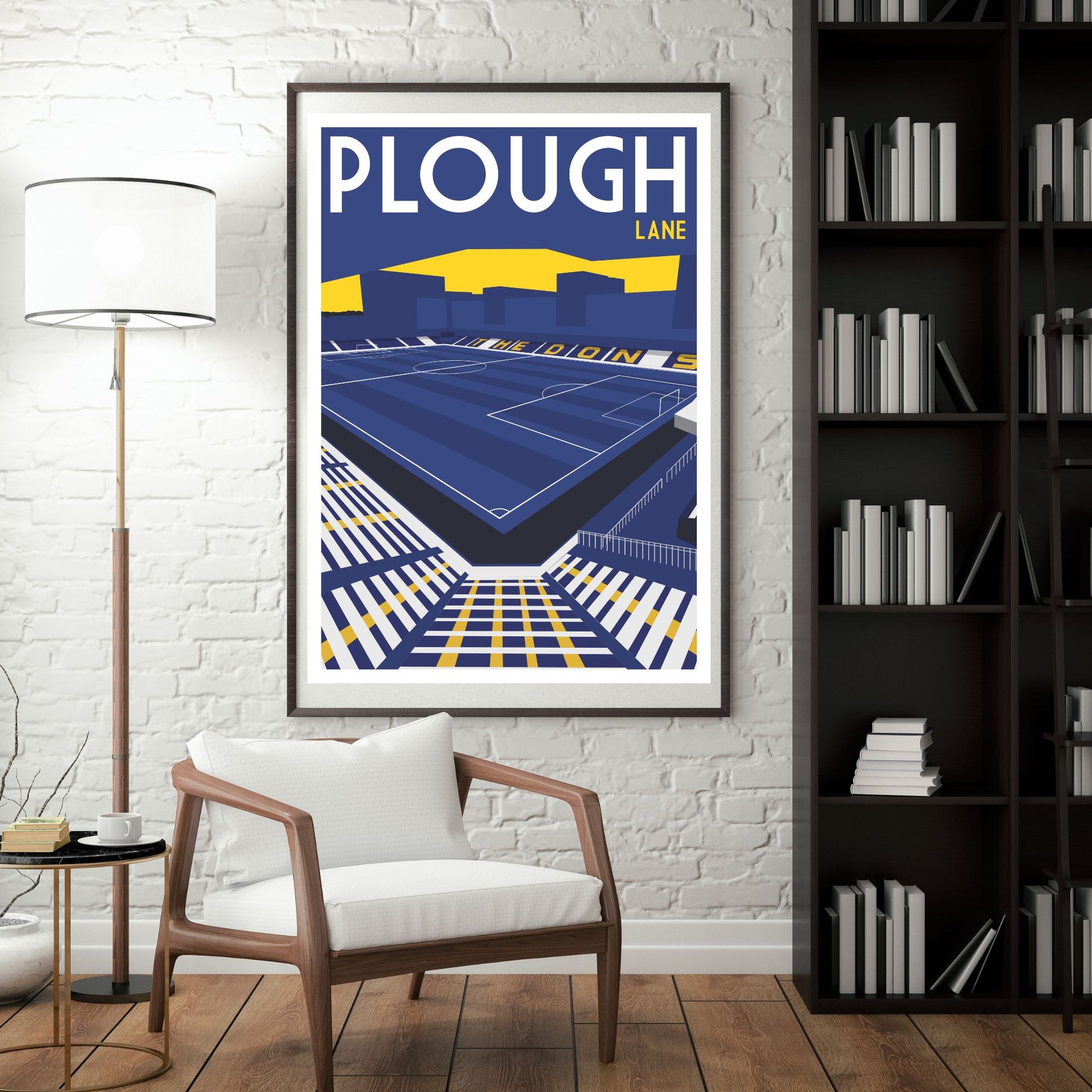a framed poster of a tennis stadium, with a white chair in the foreground and a bookshelf filled with books in the background.