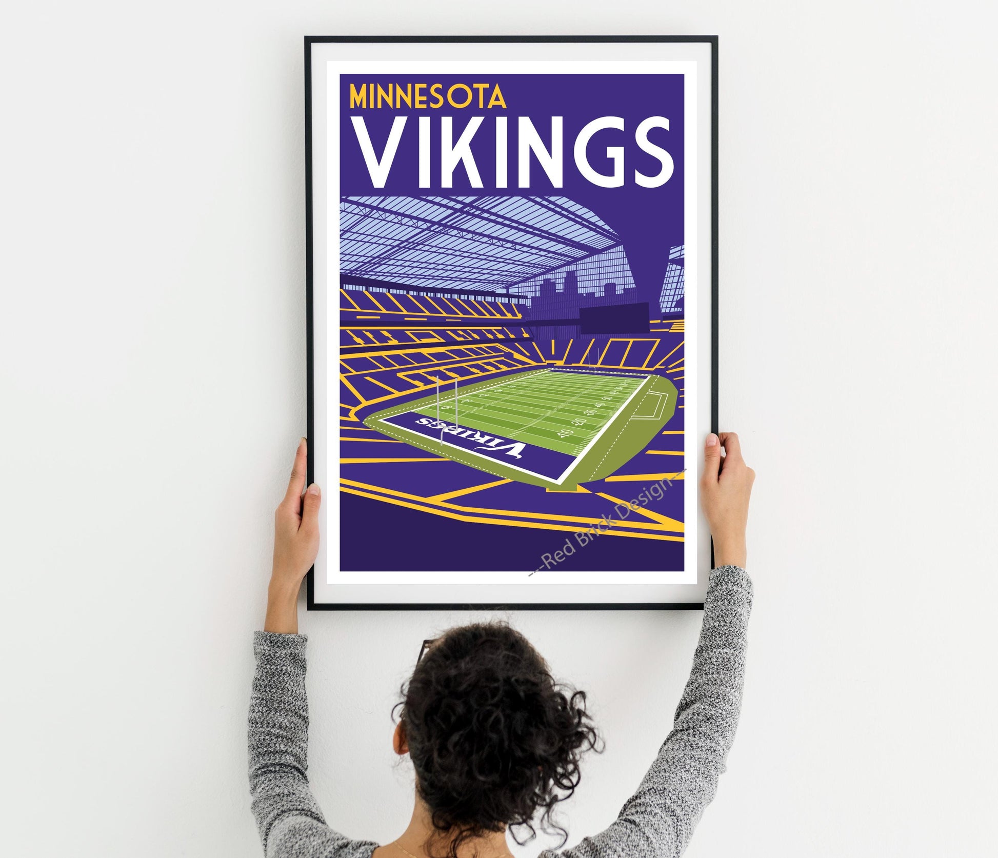 a woman holding up a framed poster of minnesota vikings