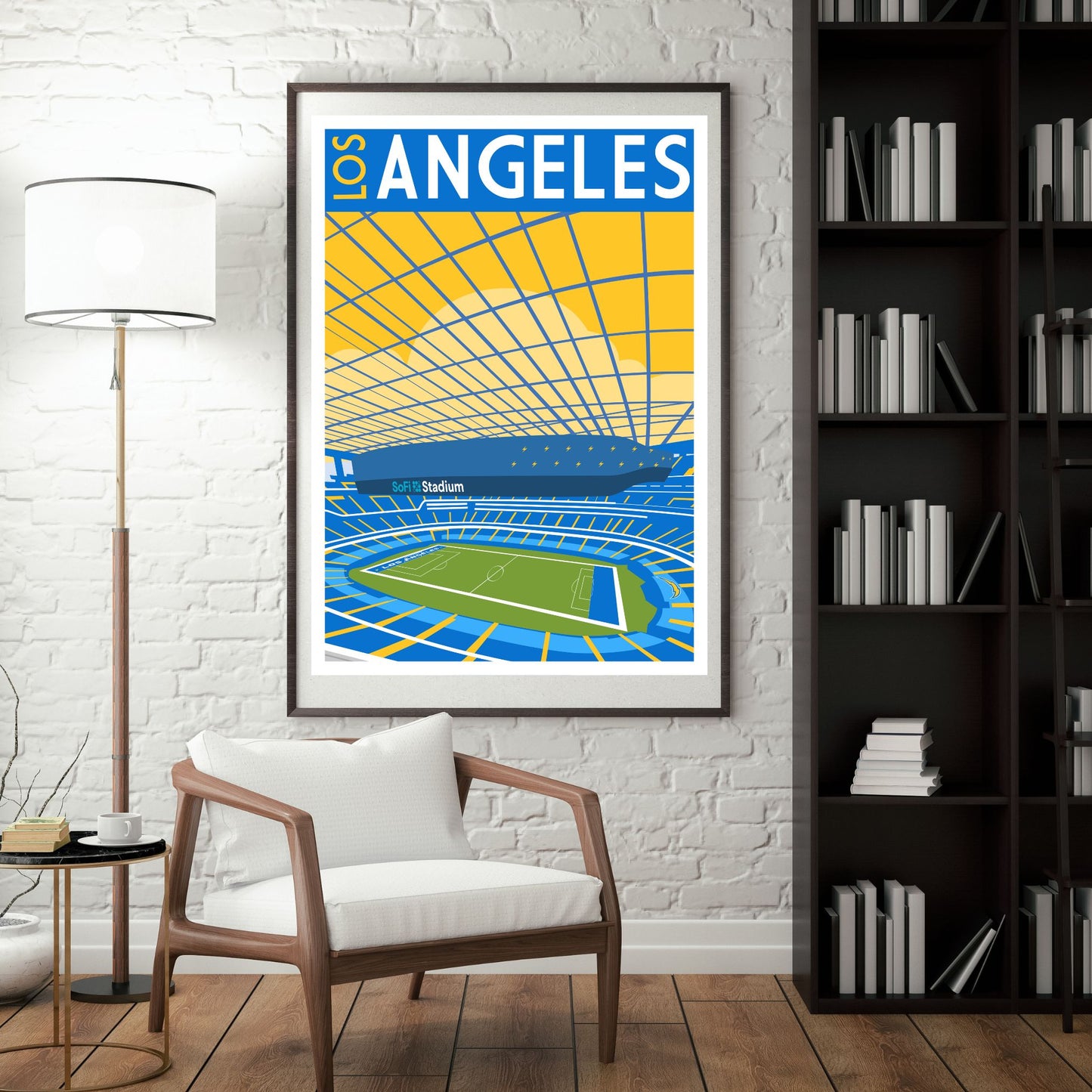 a framed poster of a stadium with a tennis court, hanging on a wall in a room with a white chair and a bookshelf.