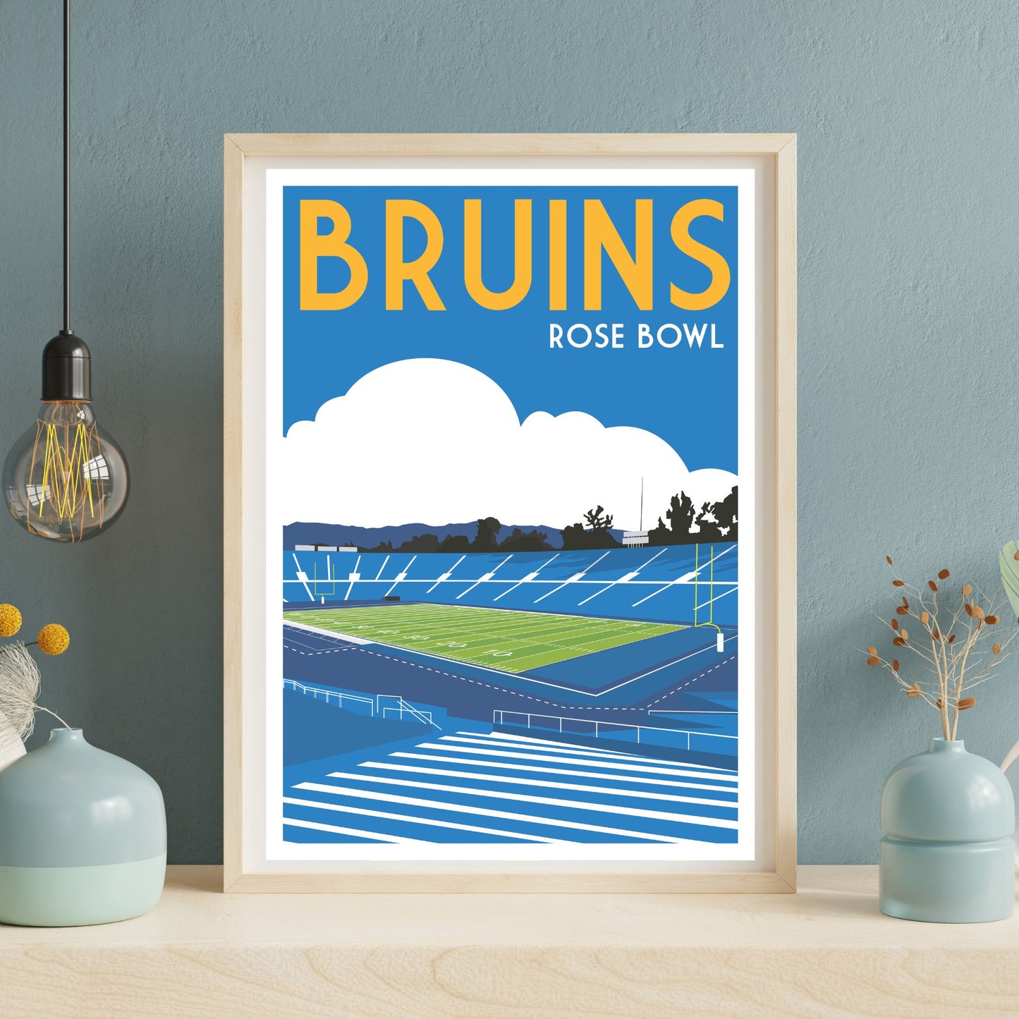 a framed poster of a sports stadium, specifically the Rose Bowl, with a blue sky and clouds in the background.