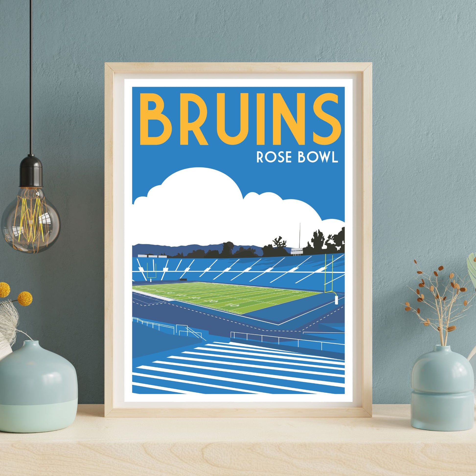 a framed poster of a sports stadium, specifically the Rose Bowl, with a blue sky and clouds in the background.
