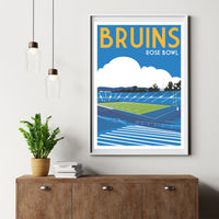 a framed poster of a sports stadium, specifically the Bruins Rose Bowl, hanging on a wall above a wooden cabinet.