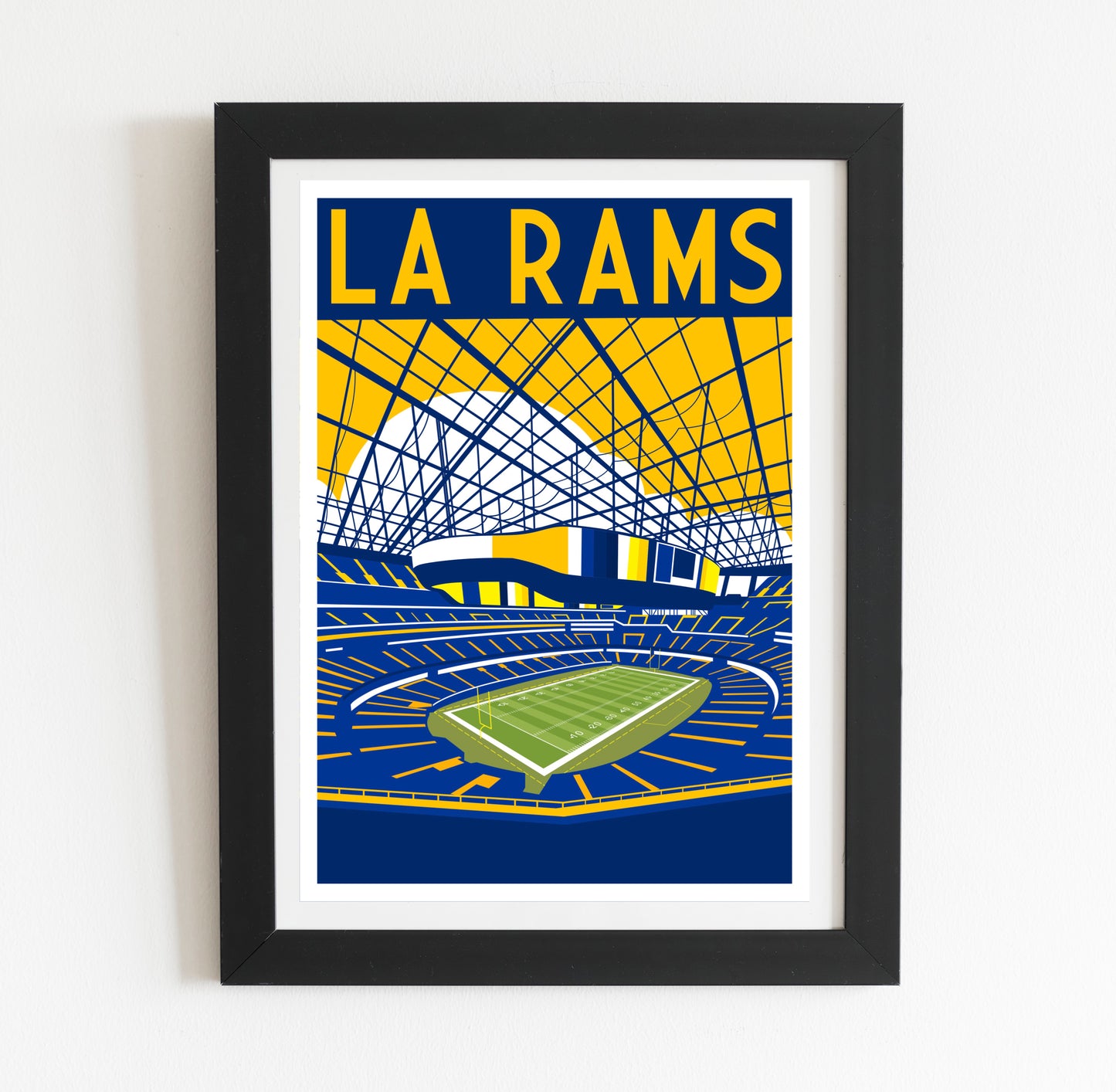 A framed poster depicting a sports stadium with a large field and a large stadium structure in the background.