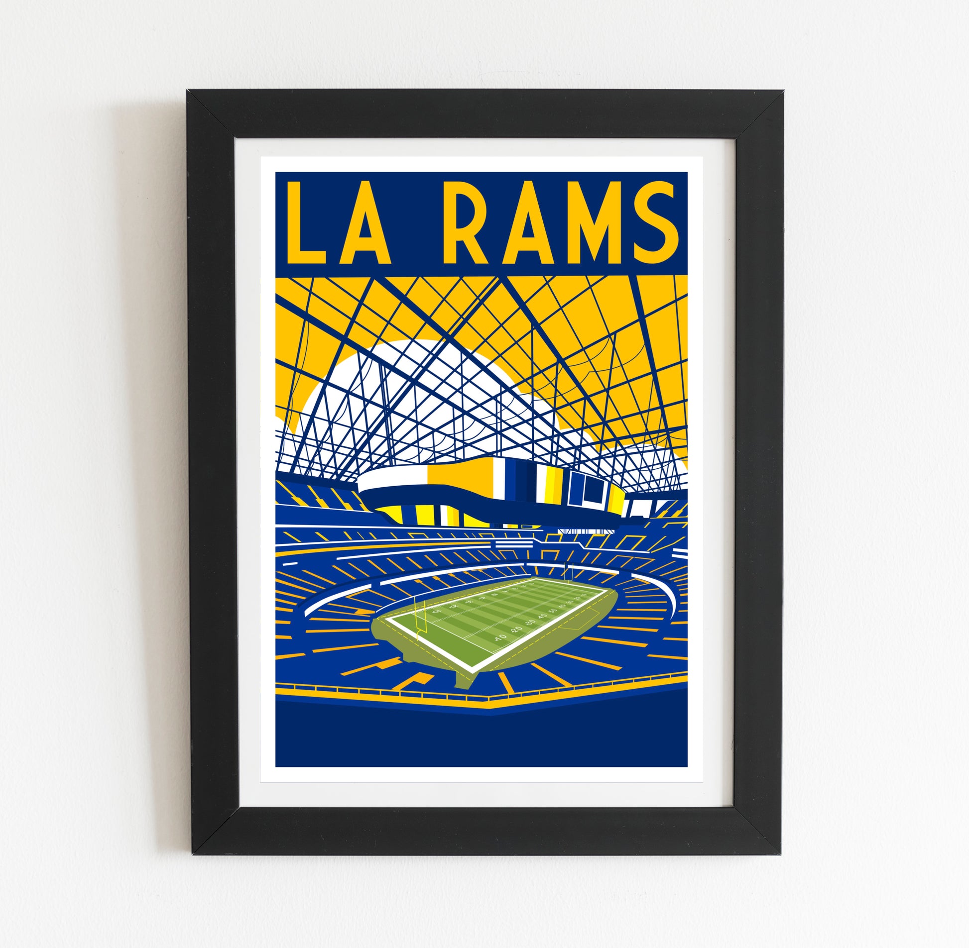 A framed poster depicting a sports stadium with a large field and a large stadium structure in the background.