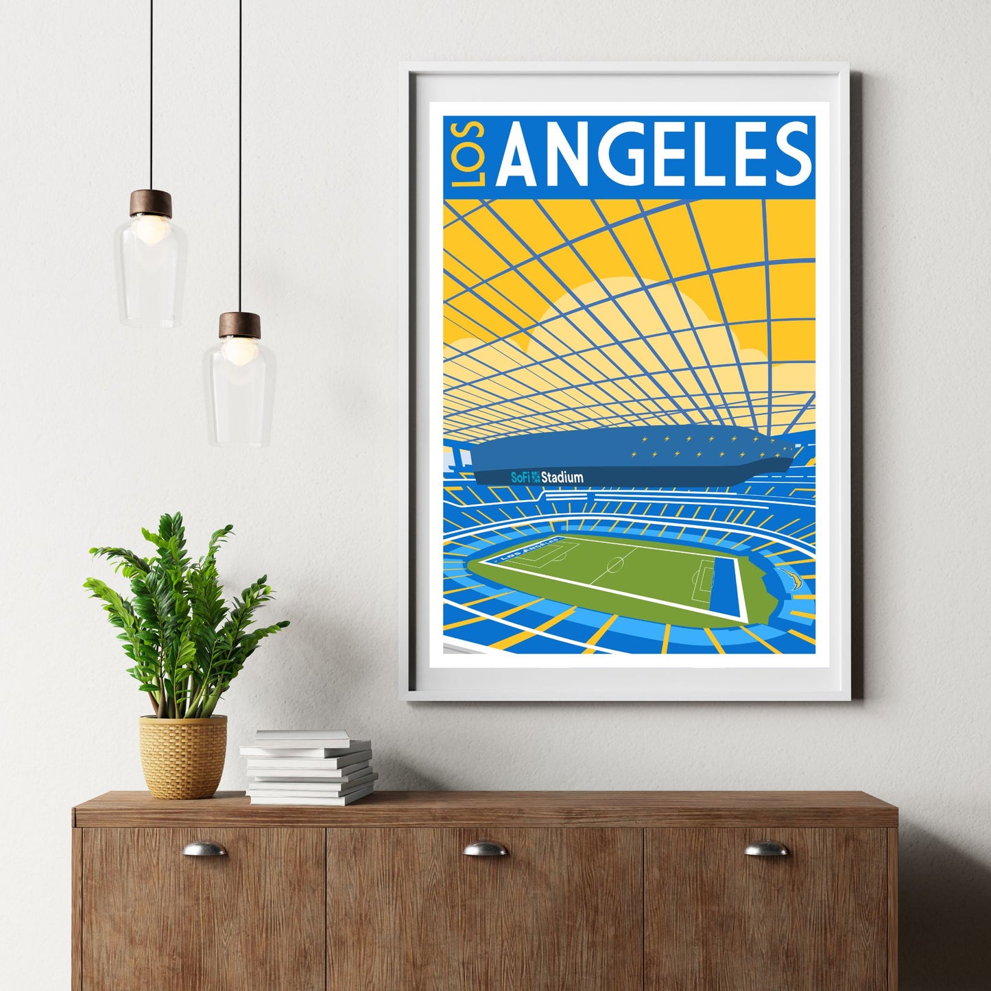 a framed poster of a stadium with a plant on a wooden dresser below it.